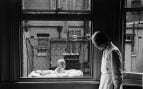 Mujer observando a un bebé en una jaula. Foto de GettyImages.
