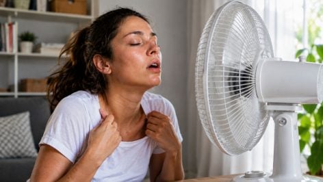 Mujer frente a un ventilador. Generado por IA.