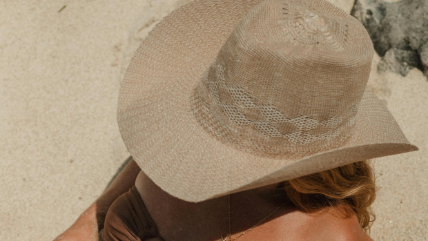 Una mujer toma el sol con un sombrero - Canva