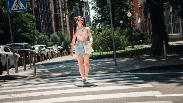 Chica cruzando la calle (Adobe)
