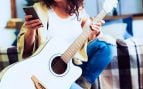 Una mujer aprende tocar la guitarra con el móvil. Foto: Freepik