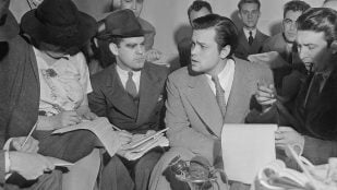 Fotografía de Orson Welles reuniéndose con periodistas en un esfuerzo por explicar que nadie relacionado con la transmisión de radio de la Guerra de los Mundos tenía idea de que el programa causaría pánico. // Noticias Acme, Dominio público, vía Wikimedia Commons