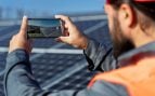 Trabajador fotografiando un campo de paneles solares. Foto: Freepik