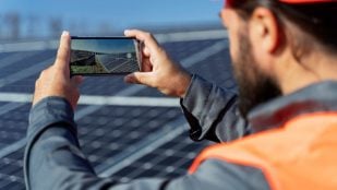Trabajador fotografiando un campo de paneles solares. Foto: Freepik