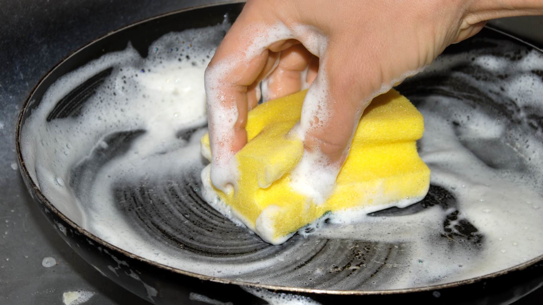 Fregando los platos con estropajo.