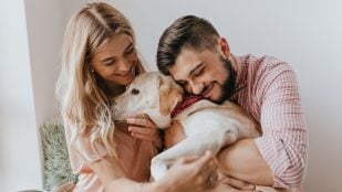 Un pareja feliz, sin hijos, abrazando a su perro. Foto: Lookstudio / Magnific