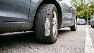 Botella en la rueda del coche (Imagen creada con IA).