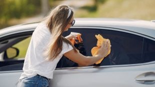 Una mujer limpia el coche bajo el sol. Foto: Magnific - @prostooleh