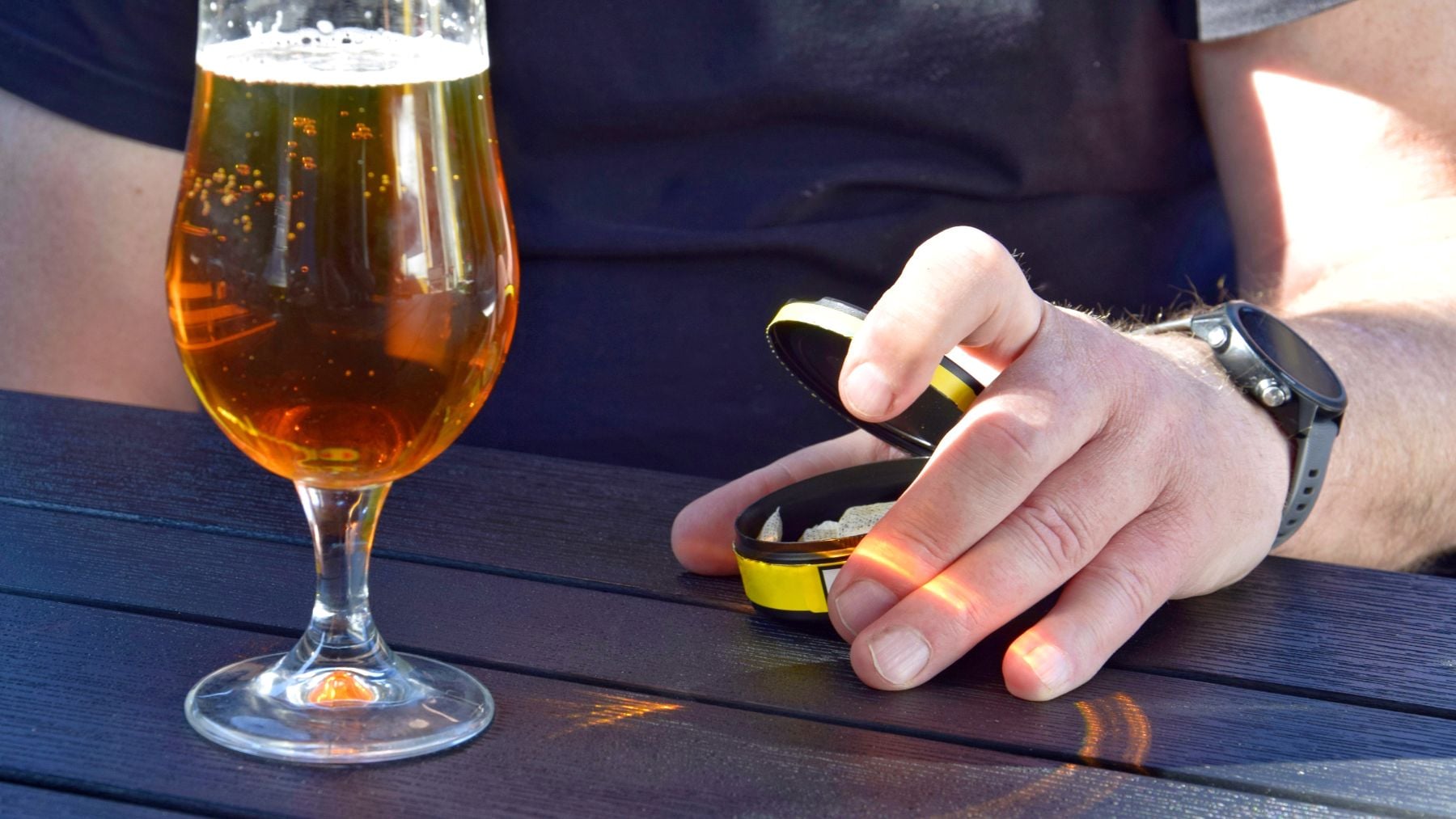 Una persona en un bar con un lata de snus.