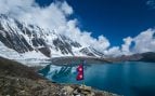 Bandera de Nepal en el lago Tilicho, con las montañas del Himalaya y los glaciares al fondo.