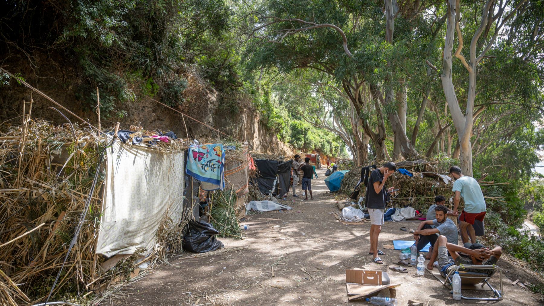 Inmigrantes acampados entre árboles en Ceuta. (Foto: Europa Press).