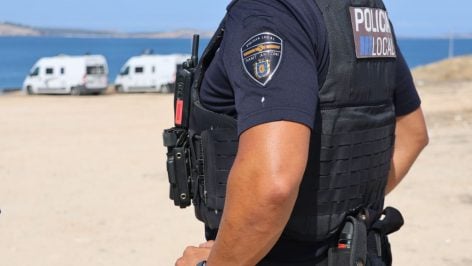 Un agente de la Policía Local con dos autocaravanas estacionadas el fondo.