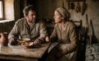 Representación fotorrealista de Sancho Panza y su esposa Teresa Panza conversando en el interior de su humilde vivienda manchega, sentados a una mesa de madera rústica con un cuenco, pan y una jarra de barro.