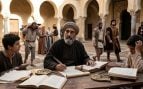 Representación fotográfica realista de Averroes (Ibn Rushd), un erudito andalusí con barba canosa y túnica tradicional, sentado pensativamente en una histórica biblioteca de patio en la Córdoba del siglo XII.