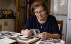Mujer mayor nacida en los años 50 o 60 mirando fotos antiguas en una mesa, recordando la época en la que tuvo que dejar los estudios para trabajar