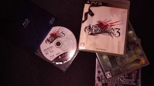 Disco de un juego de PS3 junto a un lector Blu-ray para el emulador RPCS3