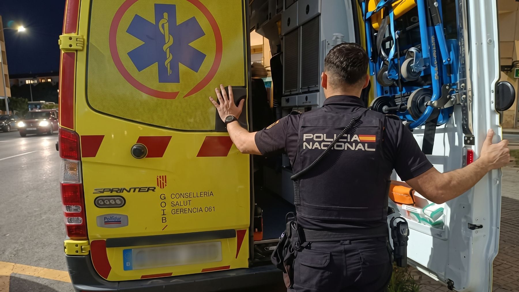 Un agente de la Policía Nacional cerrando la puerta de una ambulancia.