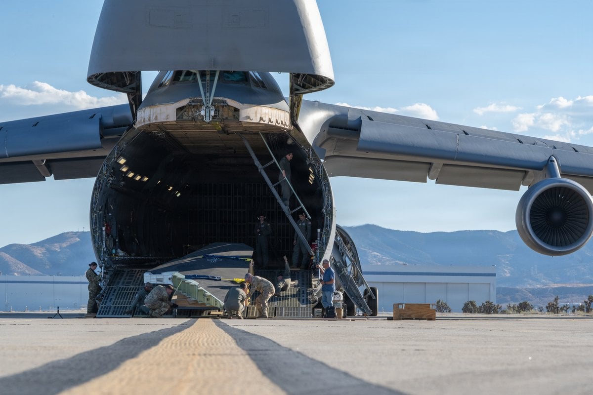 Jefes de carga de la Fuerza Aérea suben el ala izquierda del caza furtivo F-117 por la rampa delantera de un C-5M en Palmdale