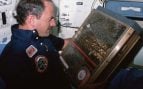 El astronauta James van Hoften sostiene la caja del experimento que llevó abejas al espacio a bordo del Challenger en 1984