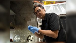 Yi Lin, de NASA Langley, sostiene una pila de botón de las baterías de estado sólido SPEARS tras la prueba de vacío térmico