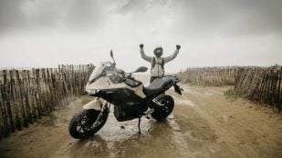Moto eléctrica de serie Zero DS en la llegada del récord Guinness de 436,5 km con una sola carga, con su piloto celebrándolo bajo la lluvia