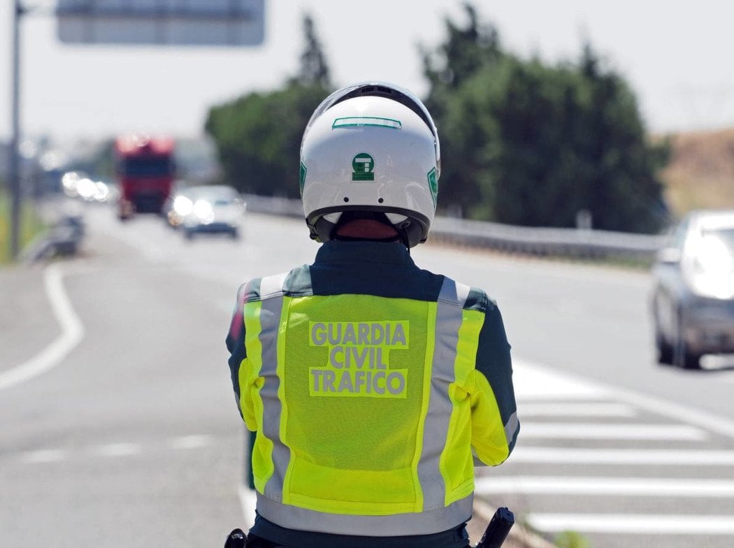 Agente de la Guardia Civil de Tráfico de espaldas en el arcén de una carretera con tráfico