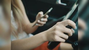 Conductora con el móvil al volante en la imagen de la nota de la DGT sobre su campaña de distracciones