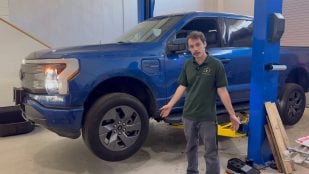 Ford F-150 Lightning Lariat azul en el elevador del taller WattWorks junto al mecánico Alex Bessinger