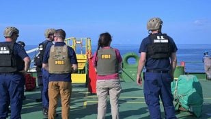 Personas con chalecos del FBI y de la Guardia Costera de EEUU en la cubierta de un buque tanque en el golfo, el 24 de agosto de 2026
