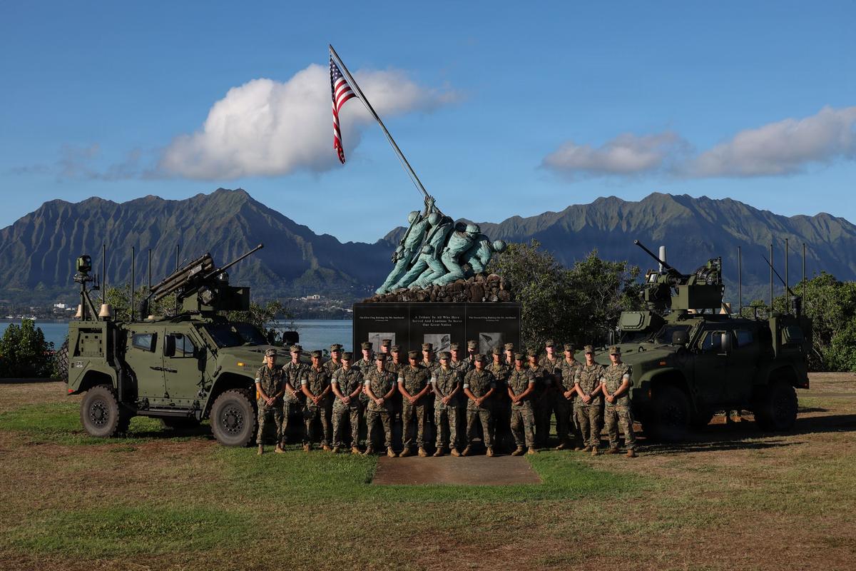 Marines del 1.er Batallón de Defensa Aérea de Baja Cota posan entre los dos vehículos del sistema antidrones MADIS en la base de los Marines en Hawái