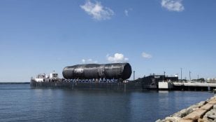 La sección del futuro USS Arizona con el primer Virginia Payload Module, cubierta con lona negra sobre una barcaza en Groton