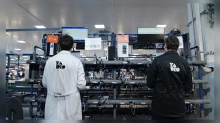 Dos operarios de Yadro ante los bancos de equipos de la planta de Dubna, que fabrica estaciones base para el 5G en Rusia