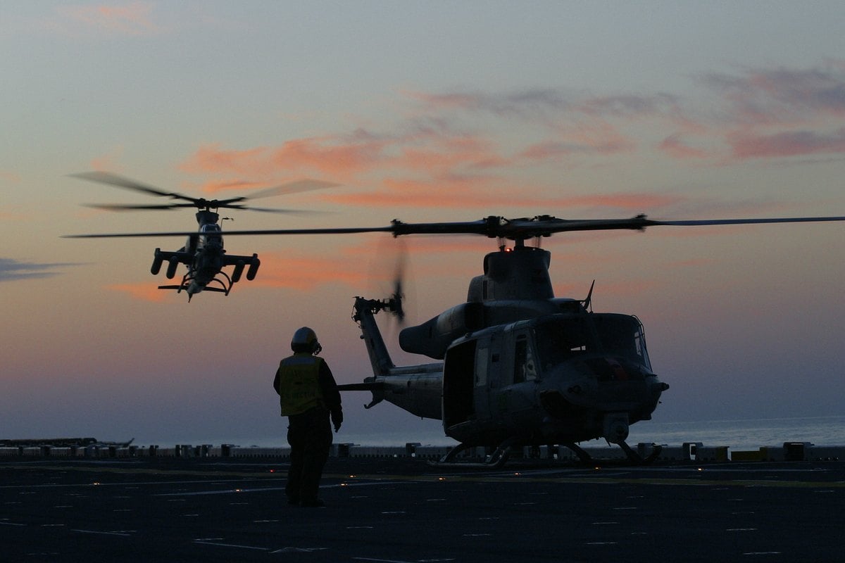 Un UH-1Y Venom en la cubierta del USS Bataan mientras un AH-1Z Viper se aproxima al anochecer durante las pruebas de mar de 2005