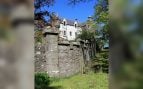 Fachada blanca del castillo Hallgreen con una torrecilla de piedra, tras un muro de piedra y un césped, en Aberdeenshire (Escocia)