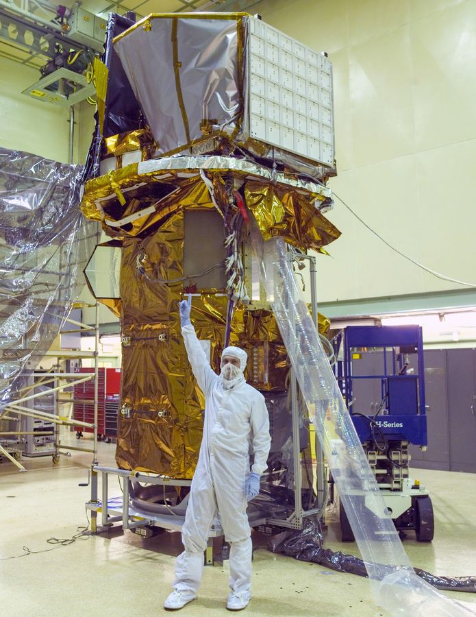 Neil Gehrels, con traje de sala limpia, señala los instrumentos del observatorio Swift en el centro Goddard de la NASA