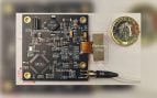 Espectrómetro en chip de la Universidad de Cambridge montado en su placa electrónica, junto a una moneda de una libra