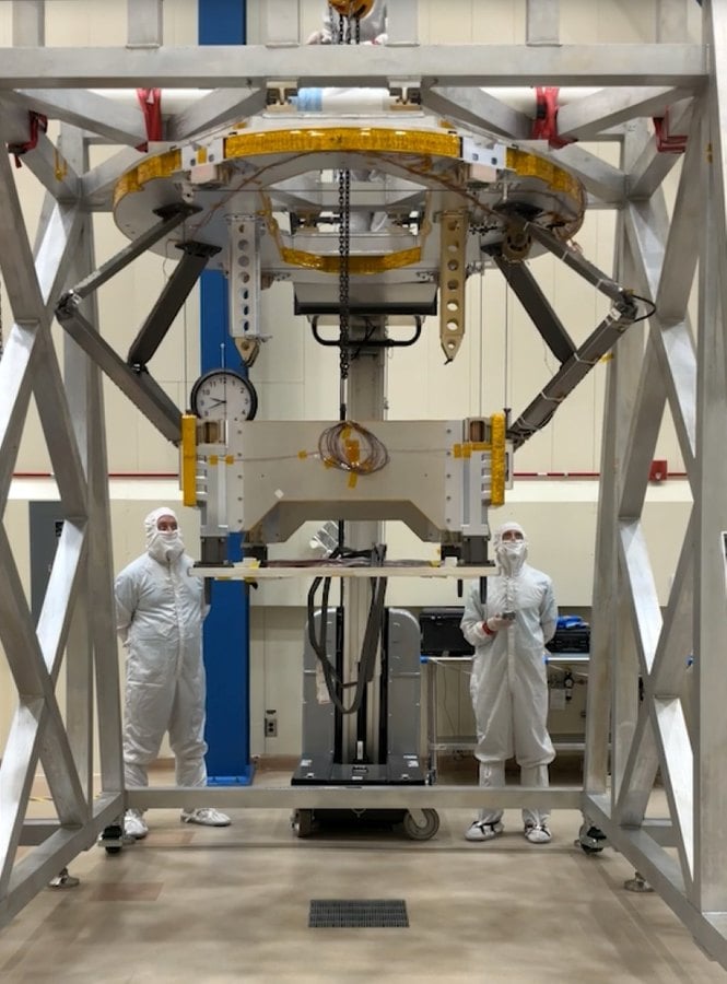 Dos ingenieros con traje de sala limpia junto al equipo de ensayo del mecanismo de pose del dron Dragonfly en Lockheed Martin