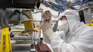 Una técnica con traje de sala limpia instala una cámara de navegación del dron Dragonfly de la NASA en el APL de Johns Hopkins