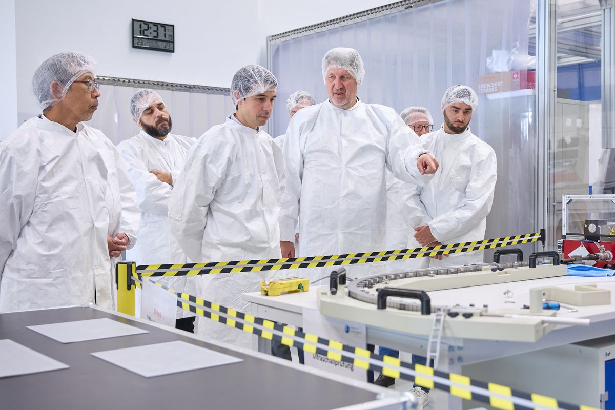 Michael Pekeler muestra una unidad orientada al plasma en la sala limpia de Research Instruments a visitantes con bata y gorro