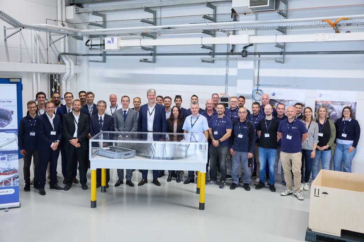 Foto de grupo del equipo de Research Instruments y F4E detrás del primer blanco vertical interior de ITER, protegido en una vitrina