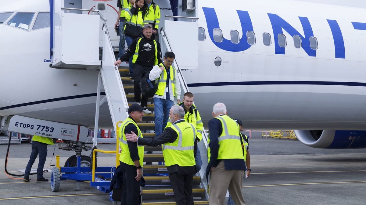 La tripulaci&oacute;n de pruebas del Boeing 737-10 baja por la escalerilla del avi&oacute;n 1G003 y la reciben directivos de Boeing con chalecos amarillos