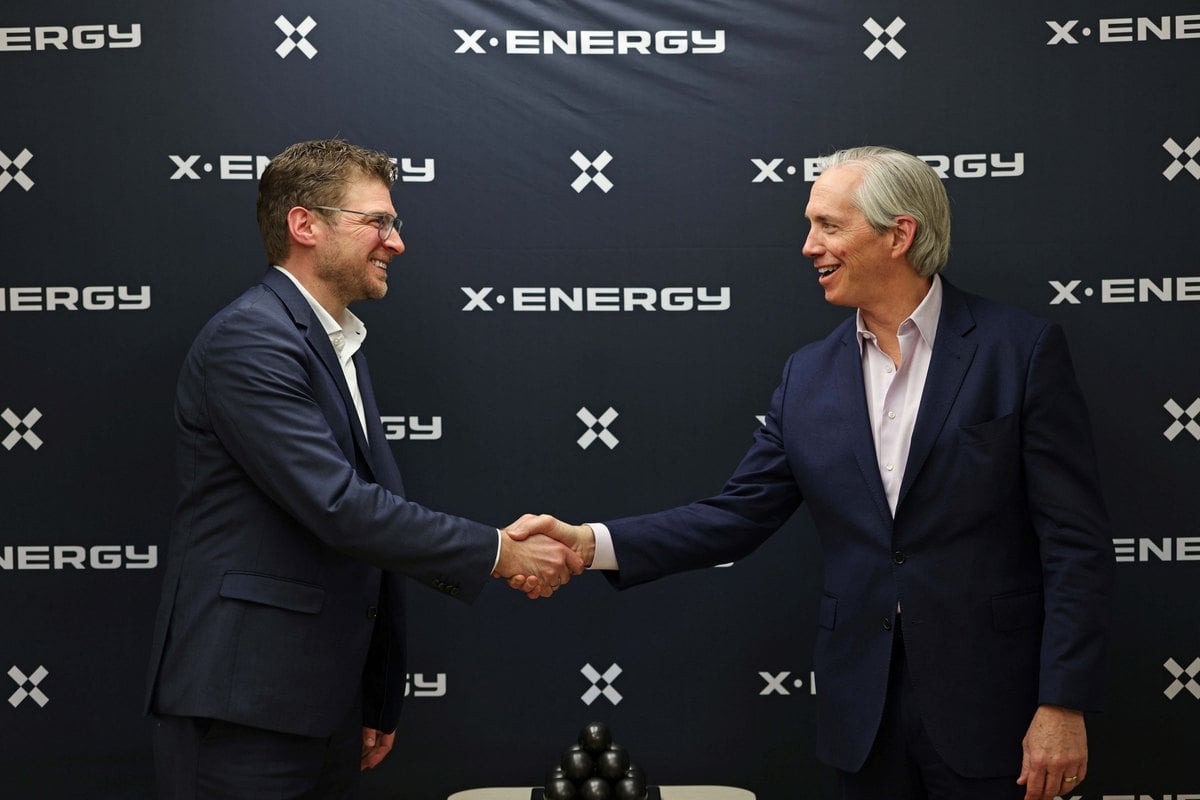 Andreas Klein, de SGL Carbon, y J. Clay Sell, de X-energy, se dan la mano ante un panel con el logotipo de X-energy