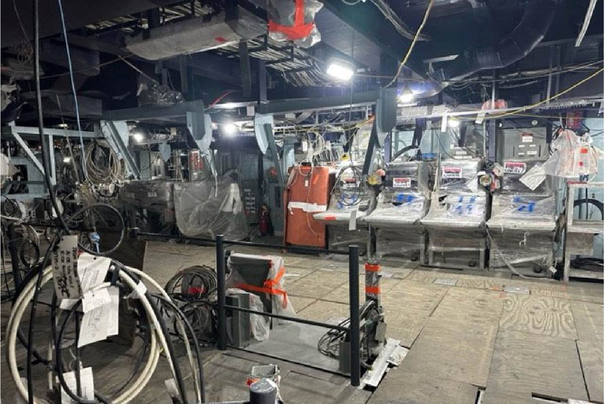 Centro de información de combate del USS Vicksburg con consolas envueltas en plástico, cables sueltos y suelo de tablones