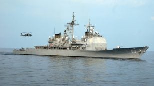 El crucero USS Vicksburg (CG 69), uno de los cruceros Ticonderoga retirados, navega por el Atlántico con un helicóptero a popa