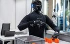 Uno de los robots humanoides de NEURA, con piel textil negra, separa piezas naranjas en una caja en la TUM RoboGym de Múnich