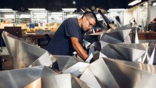 Alfonso Parra Rubio, del MIT, trabaja entre celdas de origami de aluminio plegado en un taller del Center for Bits and Atoms