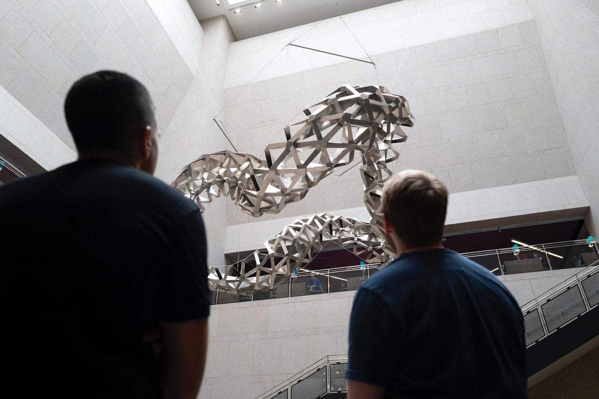 Dos visitantes miran la escultura de origami de aluminio LEXICON colgada en Deferrari Hall, en la Biblioteca Central de Boston