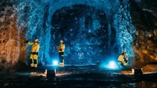 Tres técnicos de Posiva con ropa reflectante trabajan en una galería excavada en la roca del almacén de combustible nuclear gastado de Onkalo