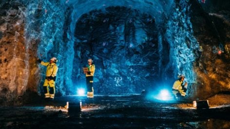 Tres técnicos de Posiva con ropa reflectante trabajan en una galería excavada en la roca del almacén de combustible nuclear gastado de Onkalo