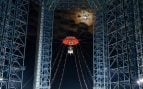 El módulo lunar Lanyue cuelga de la torre de pruebas de Huailai durante su ensayo nocturno de aterrizaje y despegue, con la Luna al fondo